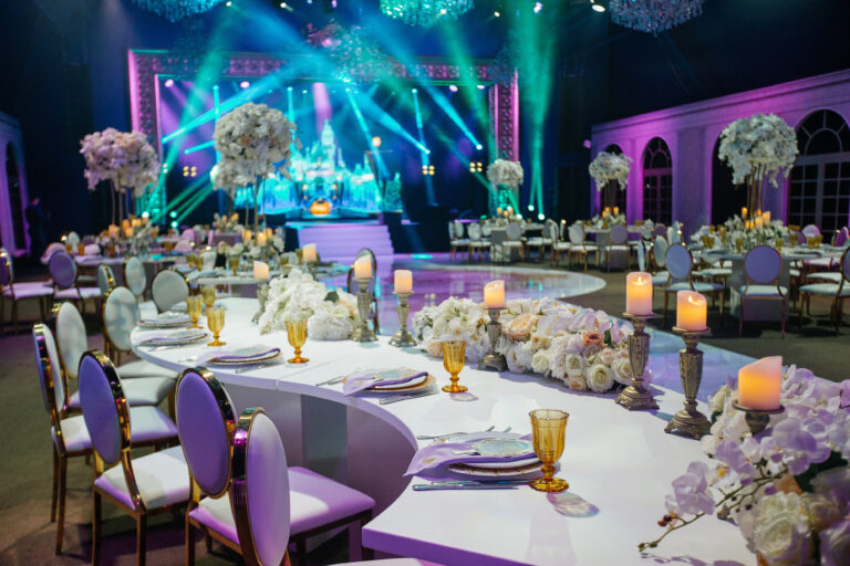 Long dinner table decorated with white flowers, shiny candles an